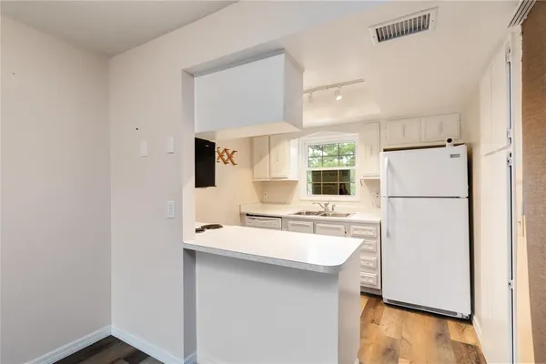 a kitchen with a sink a refrigerator and white cabinets