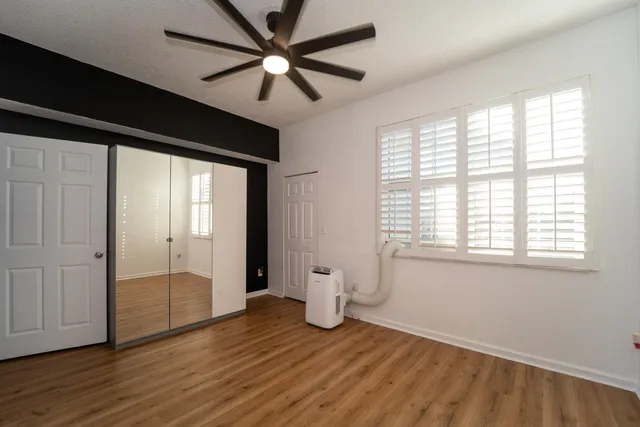 a view of an empty room with a window and wooden floor