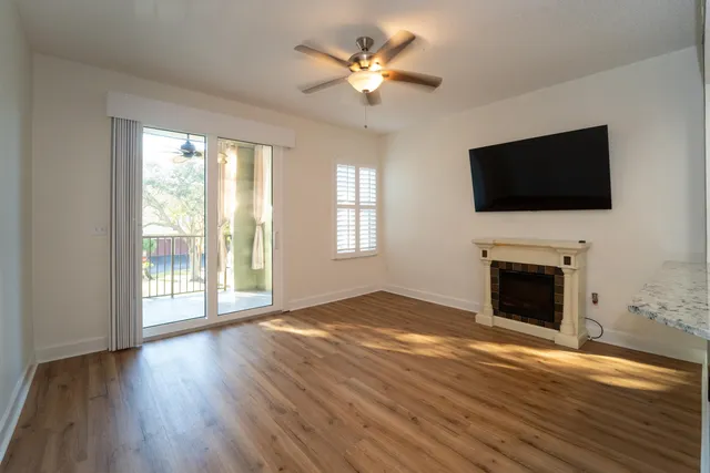 a view of an empty room with wooden floor a fireplace and a window