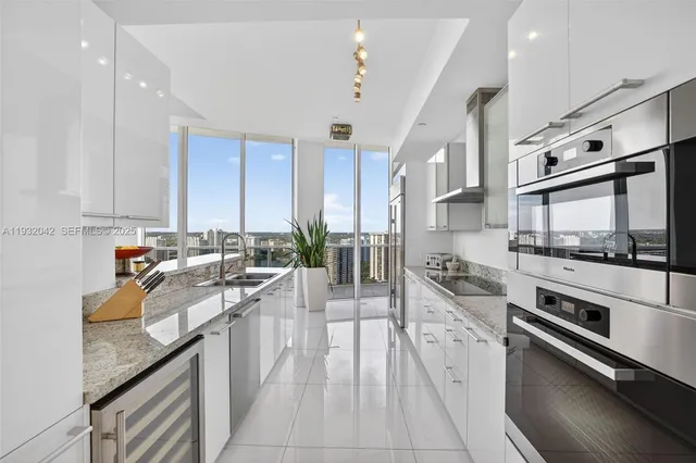 a large kitchen with stainless steel appliances granite countertop a lot of counter space and wooden floors