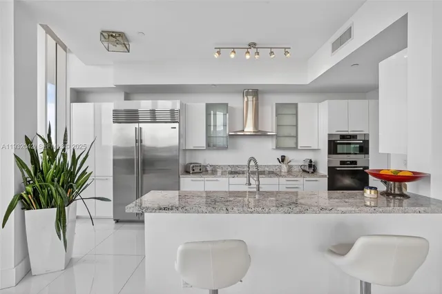 a kitchen with stainless steel appliances granite countertop a refrigerator a stove a sink a counter space and cabinets