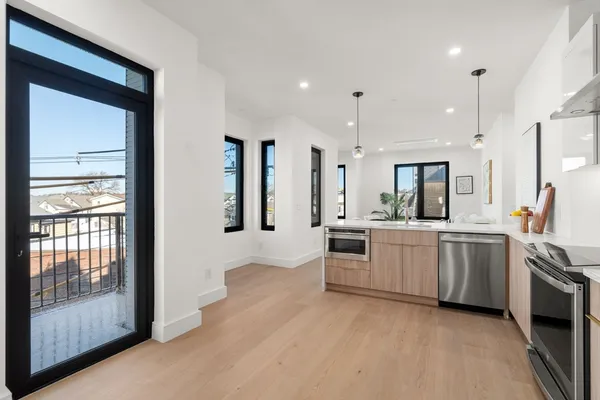 a large white kitchen with lots of counter space wooden floor and stainless steel appliances