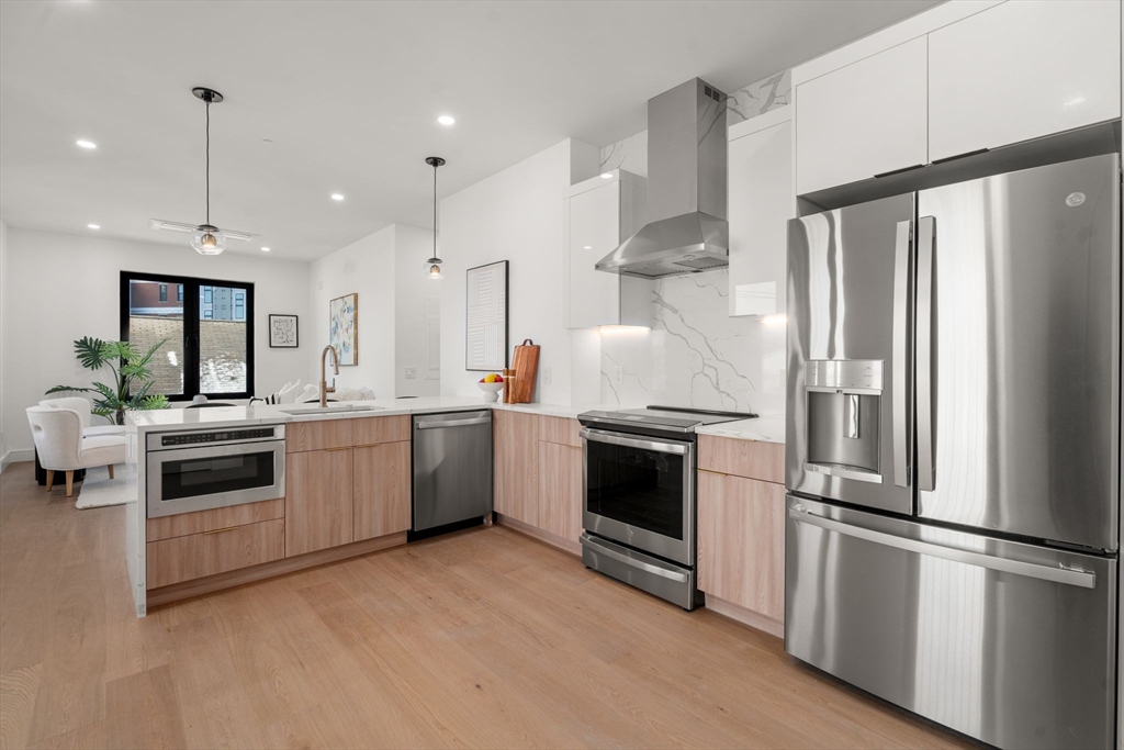 84 Prospect Street, Unit 302 Somerville, MA 02143 - Photo 4 of 9 a kitchen with kitchen island white cabinets and stainless steel appliances