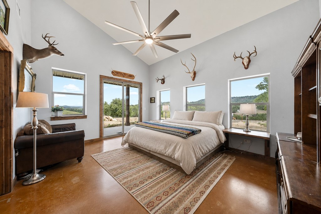 161 Balsly Road East Center Point, TX 78010 - Photo 16 of 28 a spacious bedroom with a large bed and a chandelier