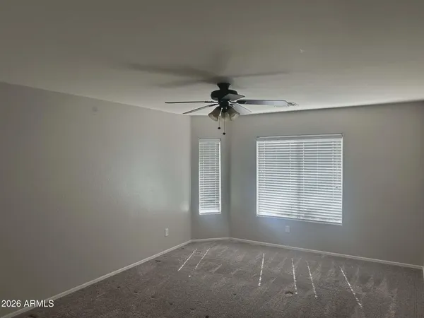 an empty room with windows and fan