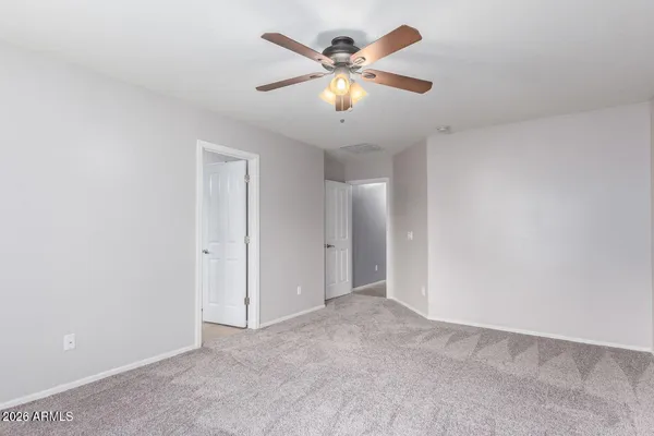 an empty room with closet and a chandelier fan