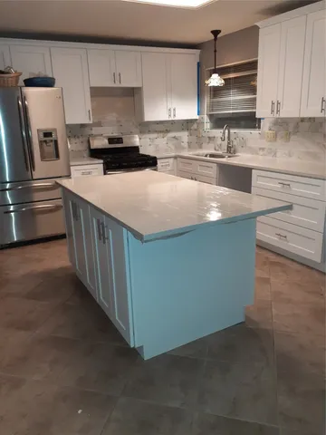 a kitchen with kitchen island a counter top space a sink and appliances