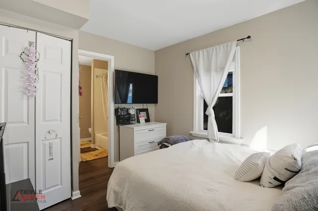 a bedroom with a bed and a flat tv screen on the dresser