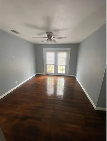 a view of an empty room with window and wooden floor