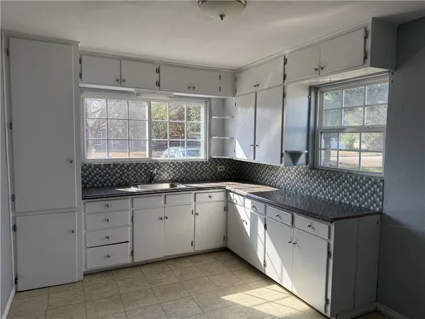 a kitchen with granite countertop a sink and white cabinets