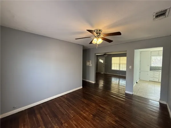 a view of an empty room with window and wooden floor