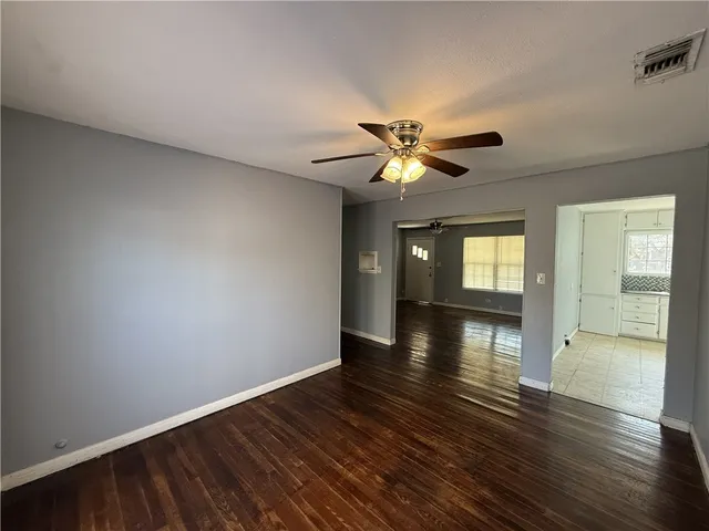 a view of an empty room with window and wooden floor
