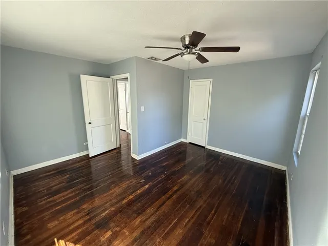 an empty room with wooden floor closet and fan