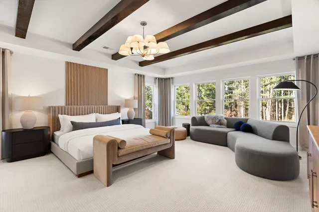 a spacious bedroom with a bed couch chandelier and a window