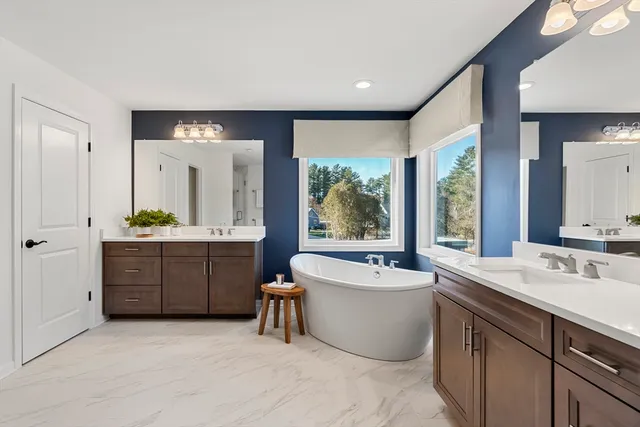 a spacious bathroom with a double vanity sink mirror and bathtub