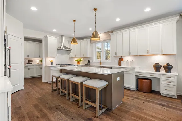 a kitchen with stainless steel appliances granite countertop a table chairs sink refrigerator and cabinets