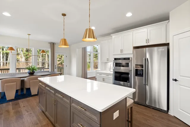 a kitchen with a refrigerator a sink and a dining table with wooden floor