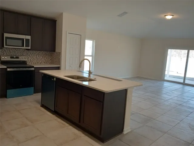 a kitchen with kitchen island granite countertop a sink dishwasher stove and cabinets