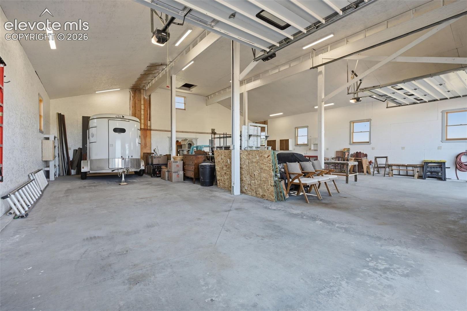 6015 West Condor Road Peyton, CO 80831 - Photo 47 of 50 Spacious concrete-floored garage with multiple windows, exposed beam ceiling, and overhead lighting