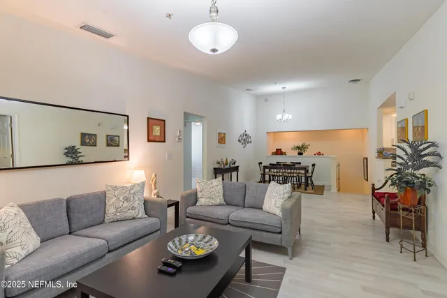 a living room with furniture kitchen view and a wooden floor