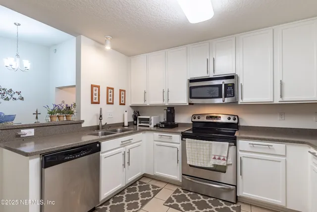 a kitchen with granite countertop white cabinets and appliances