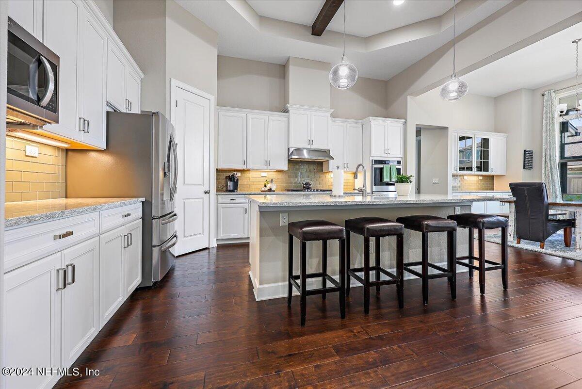 778 Glenneyre Circle St. Augustine, FL 32092 - Photo 7 of 40 a kitchen with stainless steel appliances granite countertop a dining table chairs refrigerator and sink