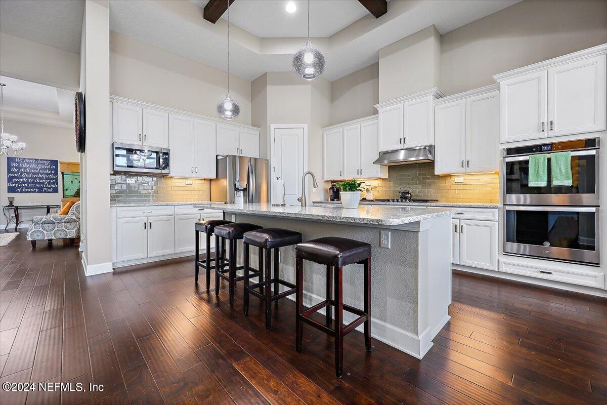778 Glenneyre Circle St. Augustine, FL 32092 - Photo 8 of 40 a kitchen with stainless steel appliances granite countertop a stove a sink a microwave a refrigerator and white cabinets with wooden floor
