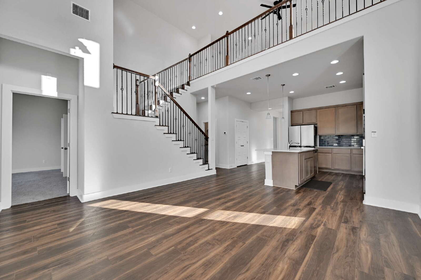 4420 Kings Cross Road Pflugerville, TX 78660 - Photo 3 of 25 Rich wood-look flooring and an elegant staircase define this soaring double-height living space.