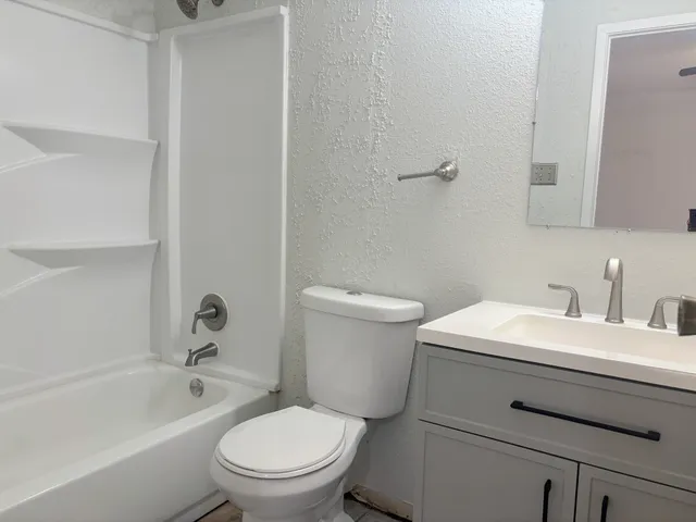 a white toilet sitting next to a bathroom sink and vanity