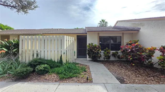 a view of a house with potted plants and a bench