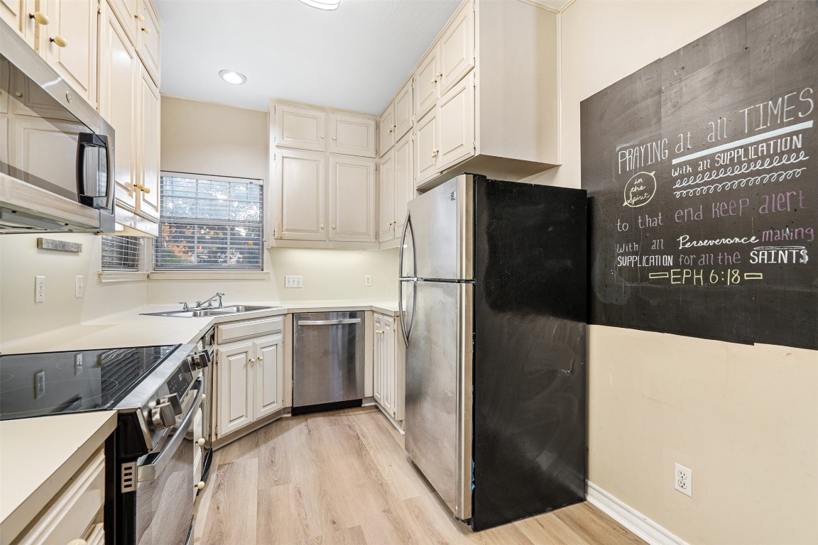 2408 Enfield Road, Unit 211 Austin, TX 78703 - Photo 11 of 26 Kitchen featuring appliances with stainless steel finishes, light countertops, light wood-type flooring, cream cabinetry, and recessed lighting