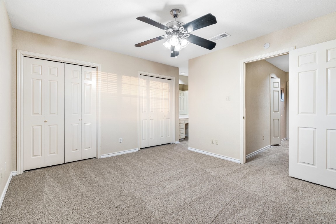 2408 Enfield Road, Unit 211 Austin, TX 78703 - Photo 16 of 26 Unfurnished bedroom with two closets, light colored carpet, and ceiling fan