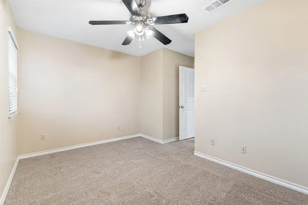 an empty room with a chandelier fan and windows
