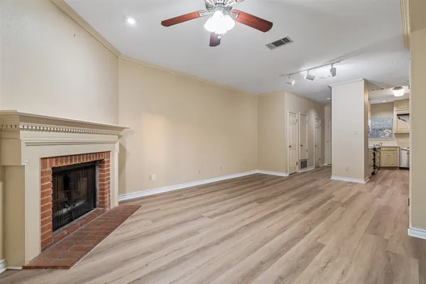 a view of an empty room with wooden floor fireplace and a window