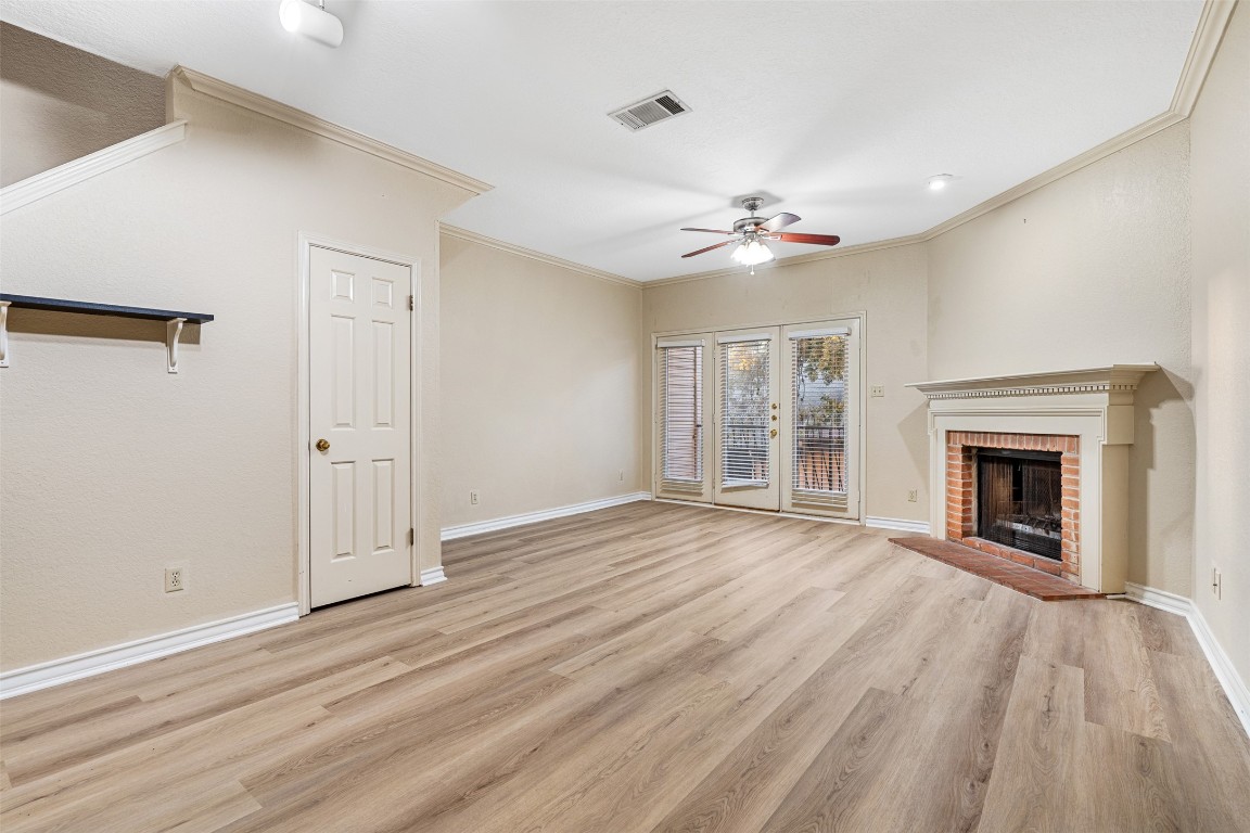 2408 Enfield Road, Unit 211 Austin, TX 78703 - Photo 6 of 26 Unfurnished living room with a ceiling fan, a brick fireplace, light wood finished floors, and crown molding