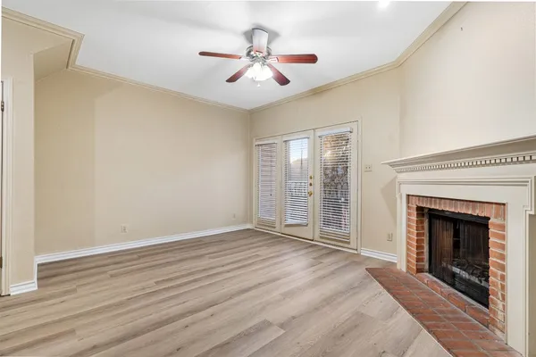 a view of an empty room with wooden floor fireplace and a window
