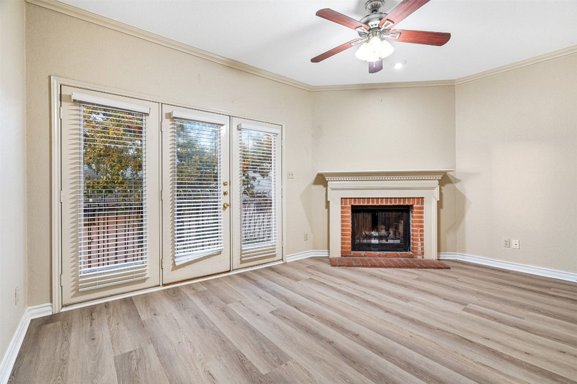 2408 Enfield Road, Unit 211 Austin, TX 78703 - Photo 9 of 26 Unfurnished living room with ornamental molding, light wood finished floors, a brick fireplace, and ceiling fan