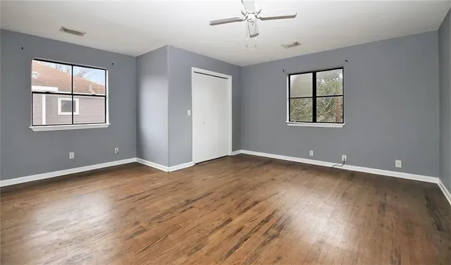 a view of an empty room with wooden floor and a window