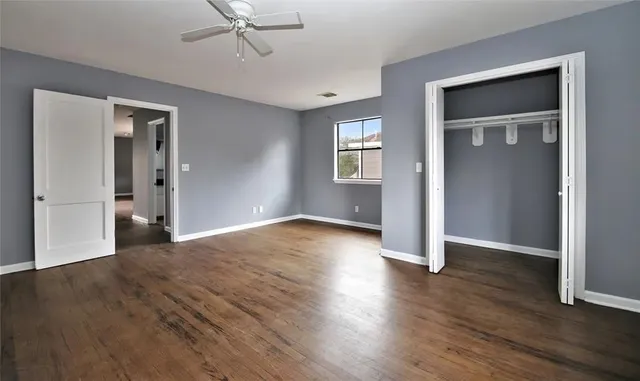 an empty room with wooden floor a ceiling fan and windows