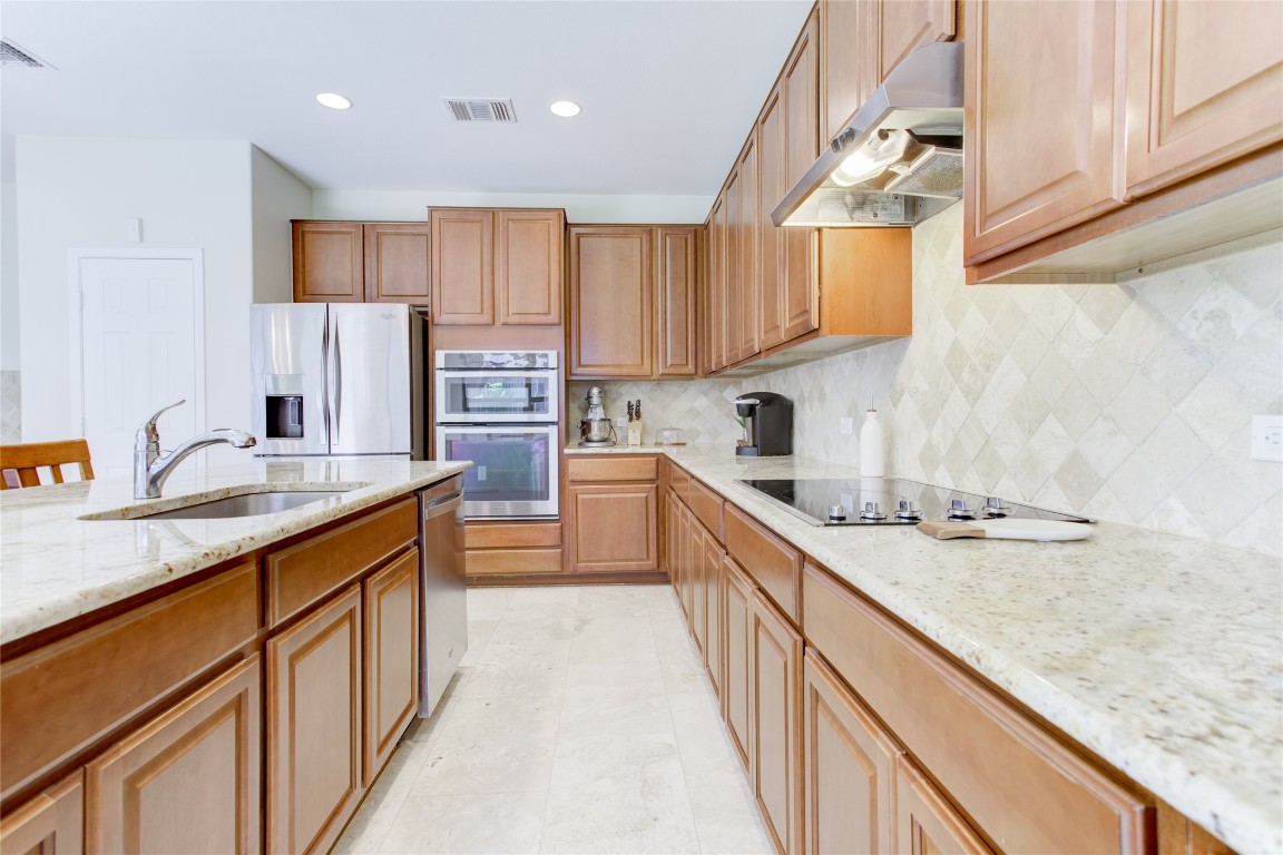 920 Autumn Sage Way Pflugerville, TX 78660 - Photo 20 of 30 a kitchen with stainless steel appliances granite countertop a sink stove and cabinets