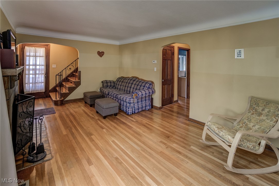 1264 Avondale Road Cleveland, OH 44121 - Photo 7 of 25 Living room featuring arched walkways, light wood-style flooring, crown molding, and stairs