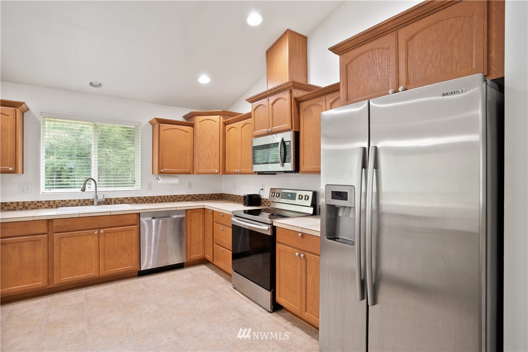4337 Maytown Road Southwest Olympia, WA 98512 - Photo 12 of 30 a kitchen with stainless steel appliances granite countertop a refrigerator a sink a stove and white cabinets