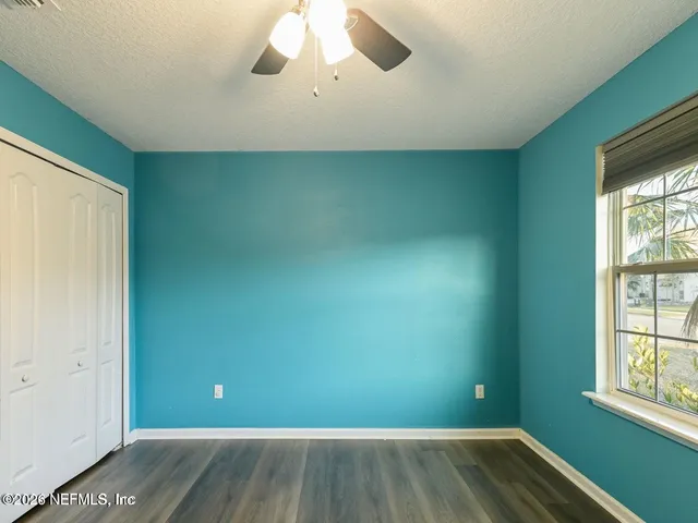 an empty room with wooden floor and windows