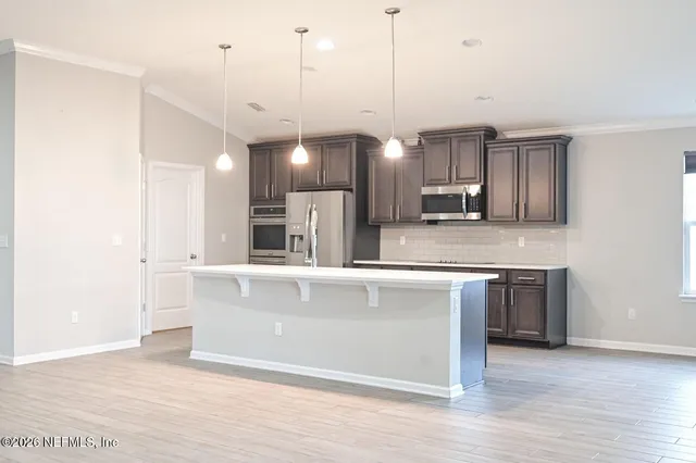 a view of a kitchen with a stove wooden cabinets and a refrigerator