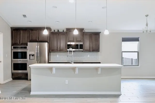 a view of a kitchen with kitchen island a sink stainless steel appliances and cabinets