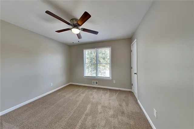 a view of an empty room with window and a ceiling fan