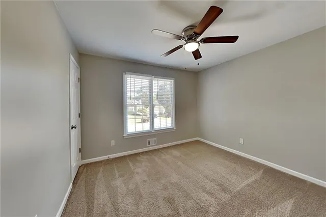 an empty room with windows and ceiling fan