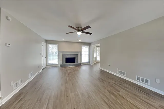 an empty room with fireplace wooden floor and windows