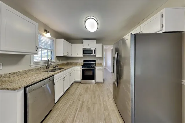 a kitchen with granite countertop a refrigerator oven a sink dishwasher and a stove with wooden floor