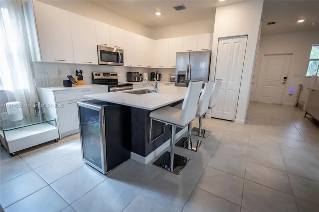 a kitchen with stainless steel appliances a stove a sink a refrigerator a microwave and a cabinets